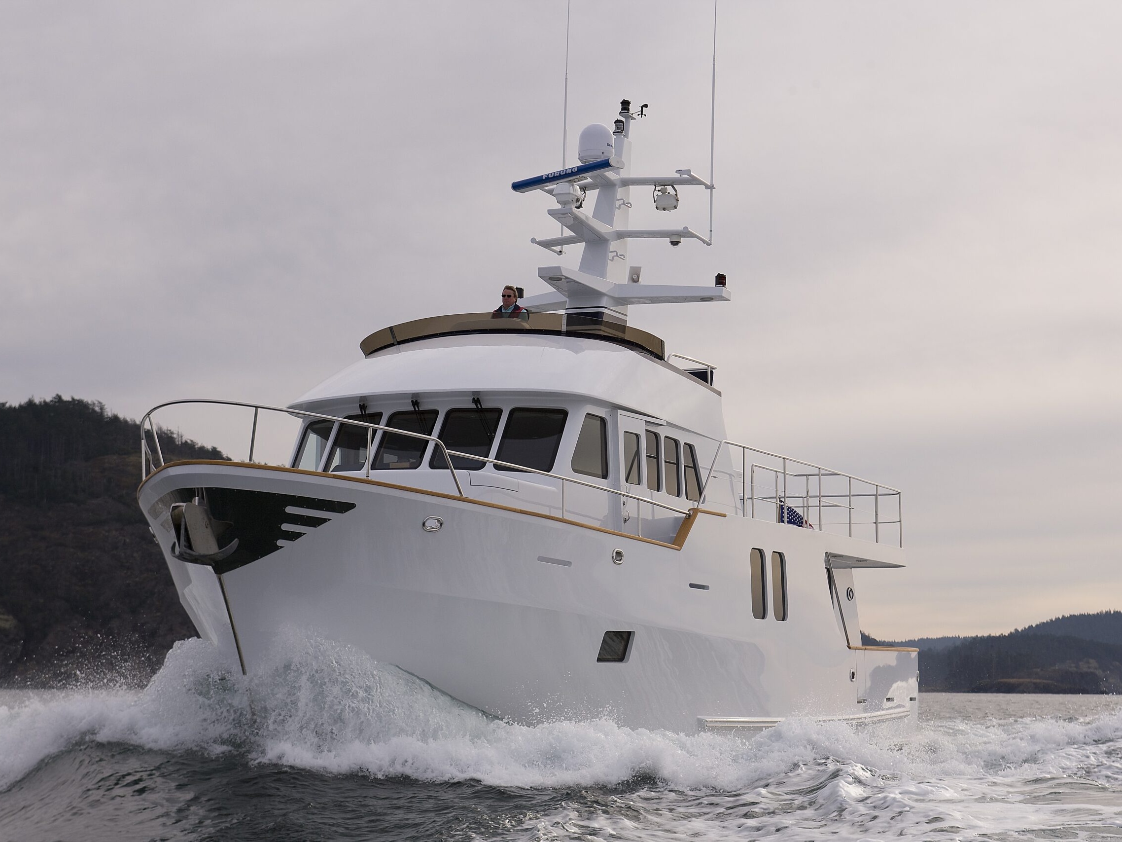 Northern Marine 64 expedition yacht cruising past mountainous Pacific Northwest coastline